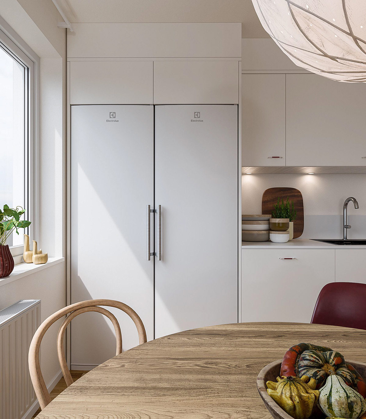 hình ảnh góc phòng bếp với tủ bếp màu trắng, bàn ăn tròn bằng gỗ, cửa sổ kính, cây xanh đặt trên bệ cửa sổ
