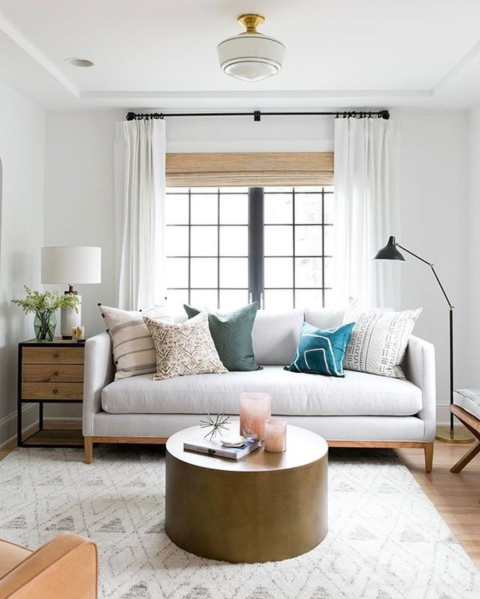 hình ảnh phòng khách với sofa màu trắng, bàn trà tròn, rèm cửa màu trắng, cửa sổ kính trong suốt
