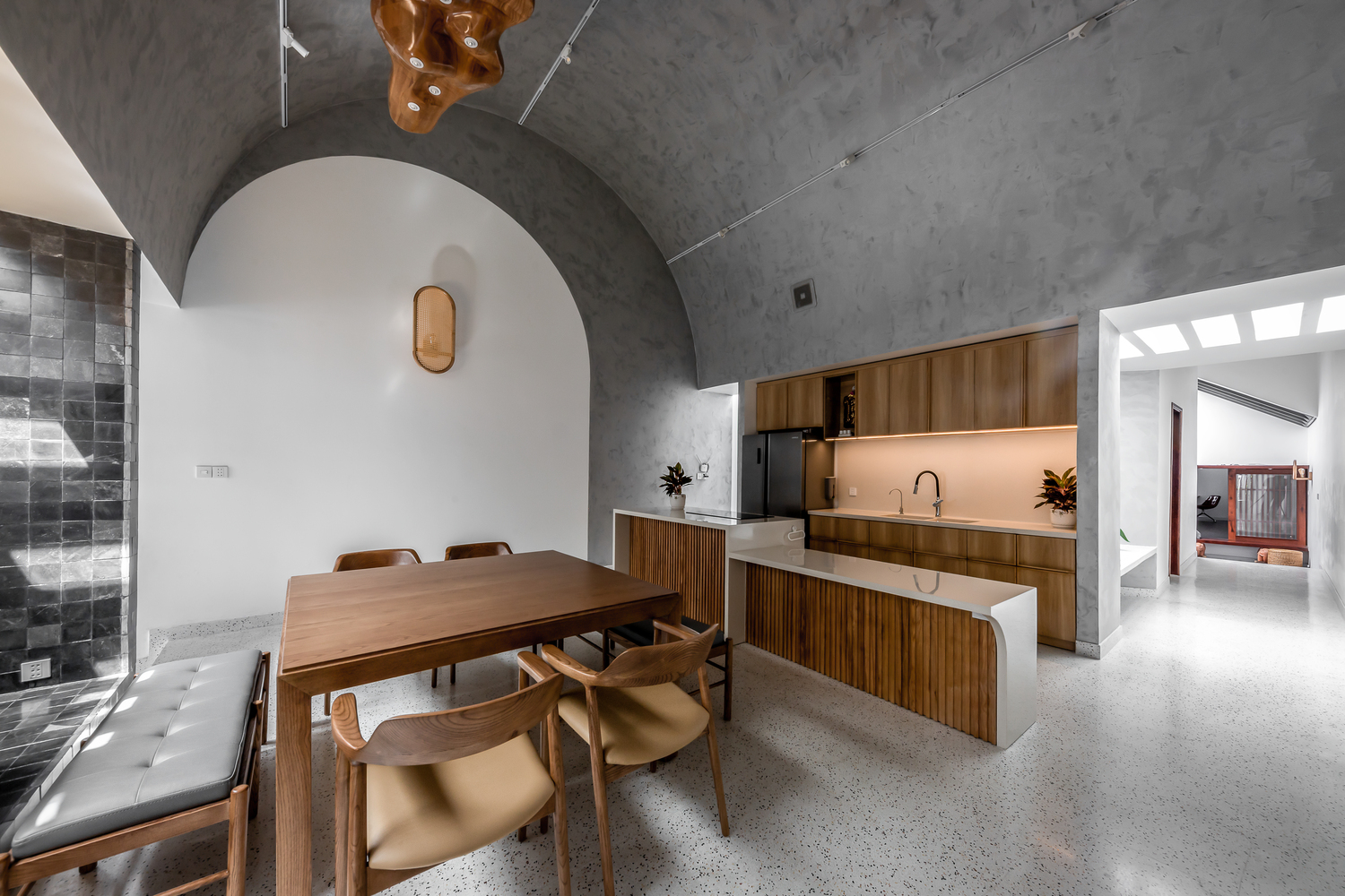 hình ảnh toàn cảnh phòng bếp ăn trong nhà ống với trần bê tông xám hình vòm, bàn ghế gỗ