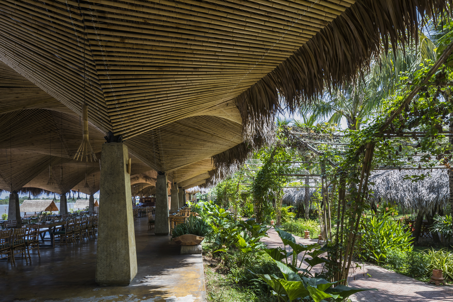 nhà hàng lợp lá dừa được bao quanh bởi cây cối xanh tốt