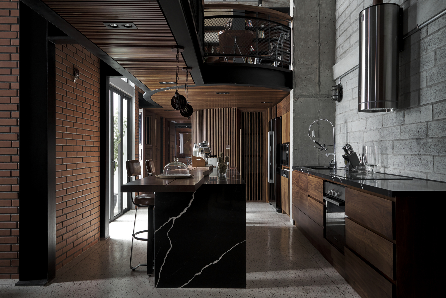 toàn cảnh phòng bếp ăn trong căn penthouse với trần ốp gỗ, tường gạch nung đỏ, bề mặt bàn đá đen