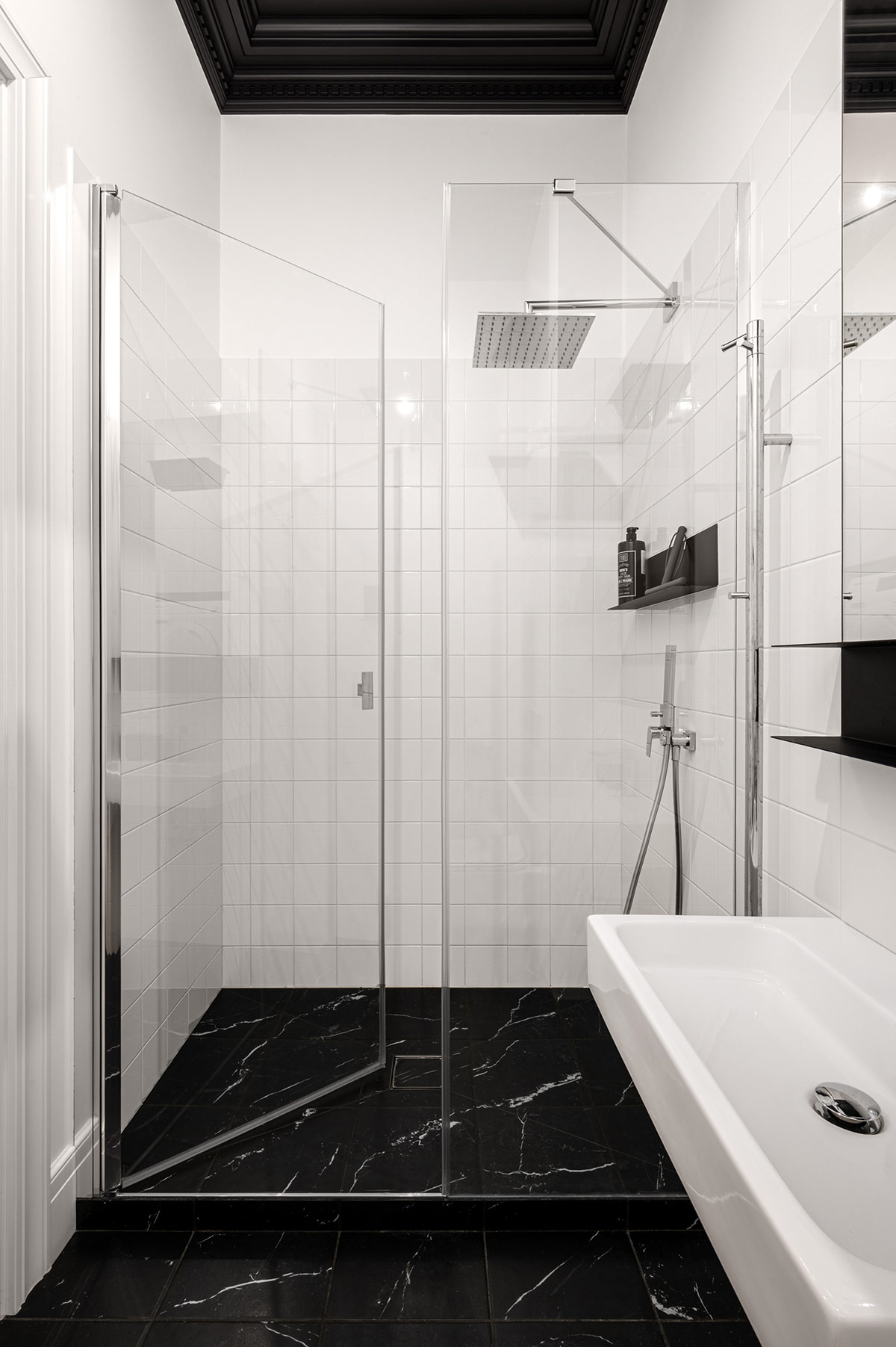 Gạch đá cẩm thạch đen giúp kết nối chặt chẽ các khu vực chức năng trong phòng tắm căn hộ tối giản này.
