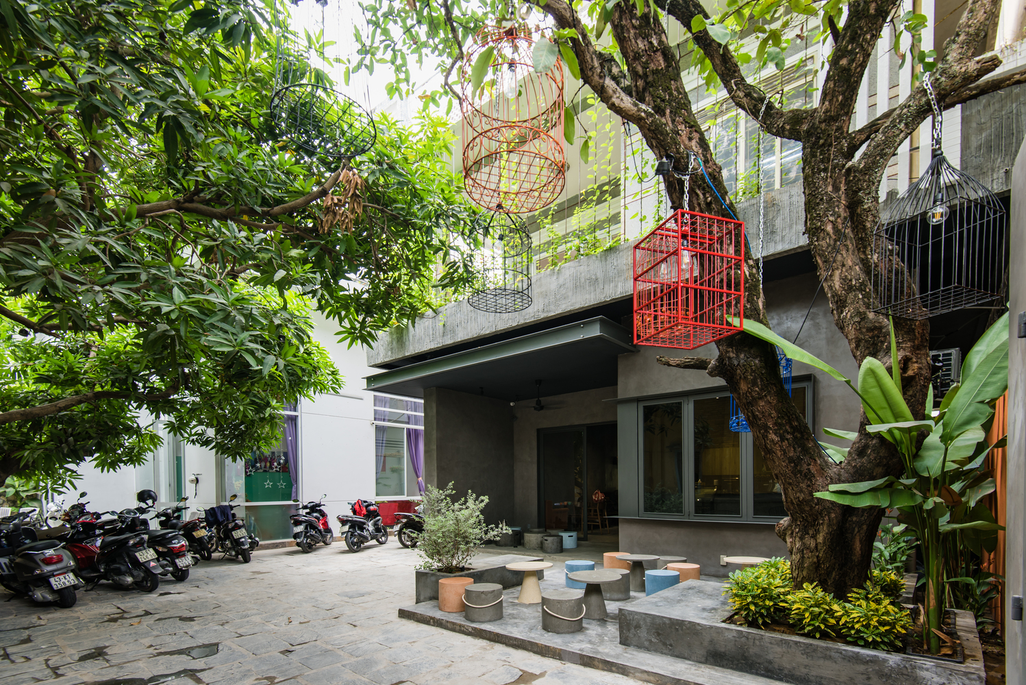 cận cảnh mặt ngoài quán cà phê đẹp the 59 ở Đà Nẵng với cây xanh, bàn ghế sắt màu sắc, lồng chim