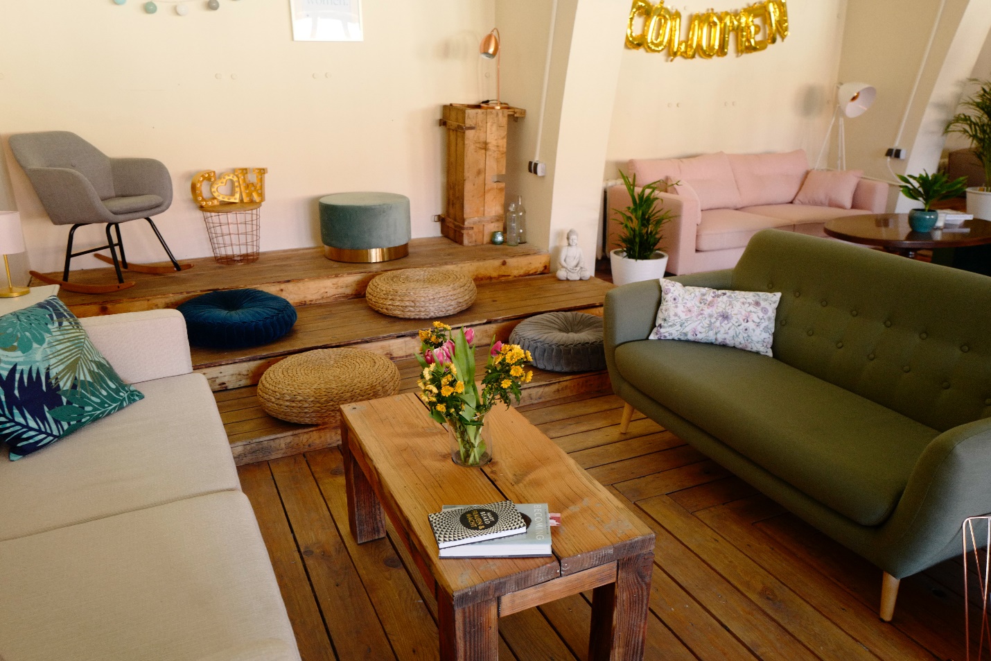 hình ảnh phòng khách nhỏ với ghế sofa màu xanh lá, bàn trà gỗ hình chữ nhật, đệm ngội trên sàn, ghế tựa màu xám