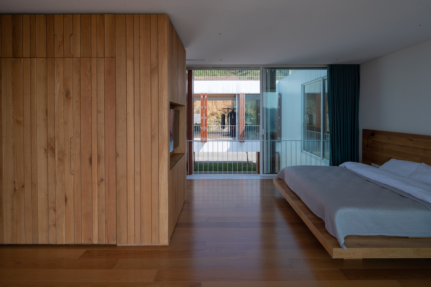 phòng ngủ với ga giường màu trắng, tủ gỗ, lan can, thông tầng