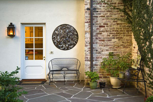 hình ảnh góc sân vườn với tường gạch trần màu xám, bàn ghế ngồi thư giãn