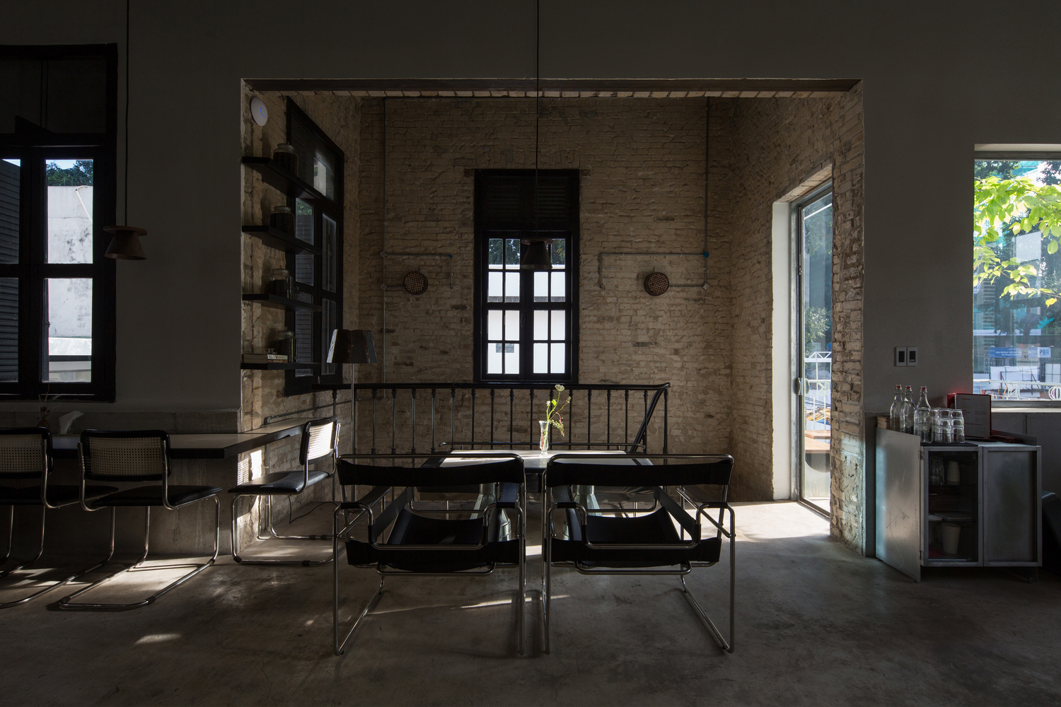hình ảnh không gian bên trong quán cà phê với tường bê tông thô mộc, bàn ghế kiểu dáng hiện đại