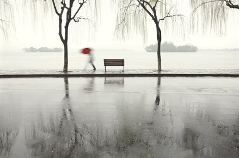 hình ảnh khung cảnh thời tiết nồm ẩm, mưa phùn gió bấc, người cầm ô đỏ đi trong mưa, cạnh hồ nước lớn