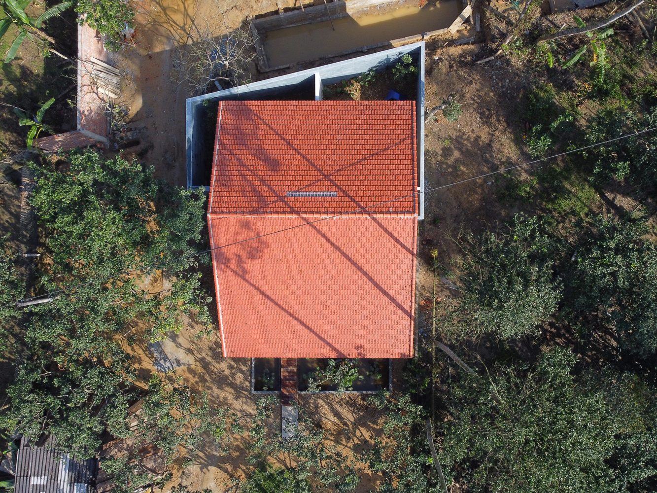 Ngôi nhà nhìn từ trên cao, với mái ngói đỏ ấm áp nổi bật giữa sắc xanh thiên nhiên.