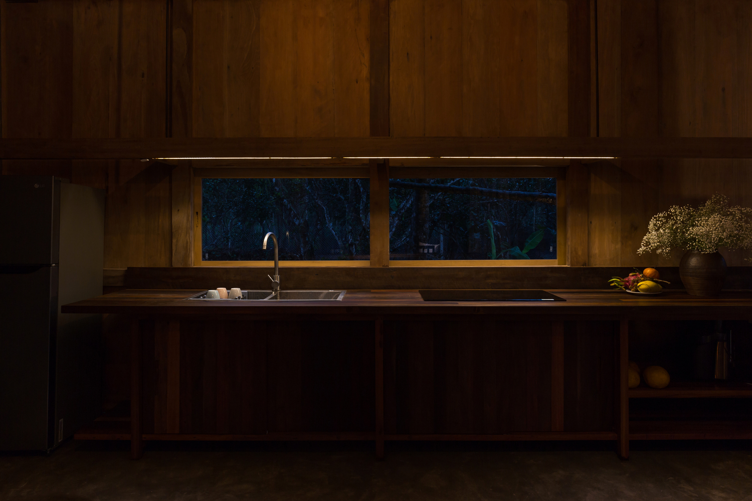 phòng bếp ban đêm với ánh đèn vàng ấm áp, cửa kính mở ra bên ngoài