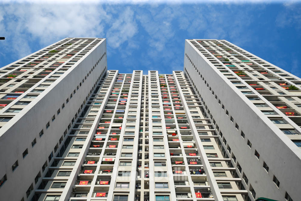 hình ảnh cận cảnh các tòa chung cư cao tầng nhìn từ dưới lên, các căn hộ treo cờ đỏ sao vàng