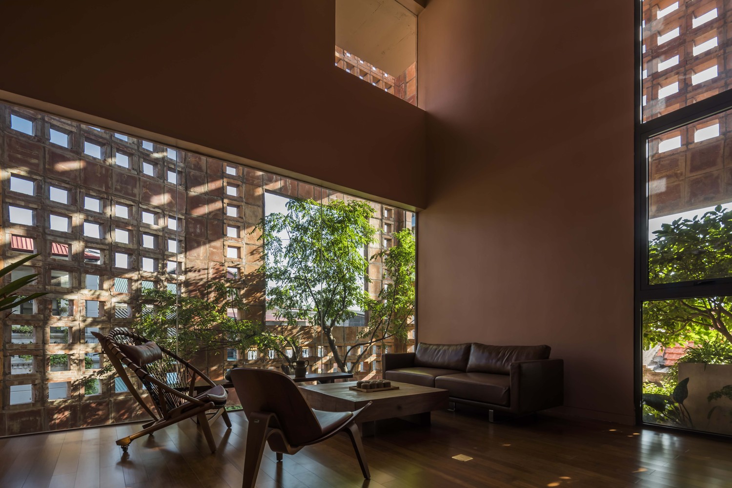 toàn cảnh phòng khách với bàn trà gỗ thấp, ghế tựa thoải mái, cây xanh trồng ở giếng trời