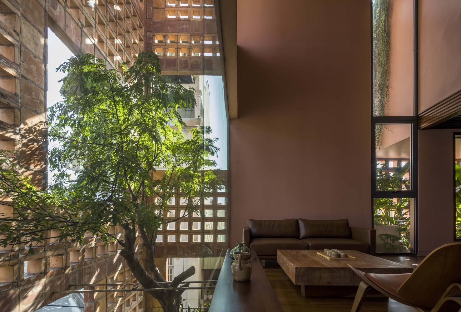hình ảnh phòng khách trong nhà gạch gốm ngập tràn ánh sáng tự nhiên chiếu xuyên qua lớp tường gạch gốm, cây xanh trồng ở giếng trời