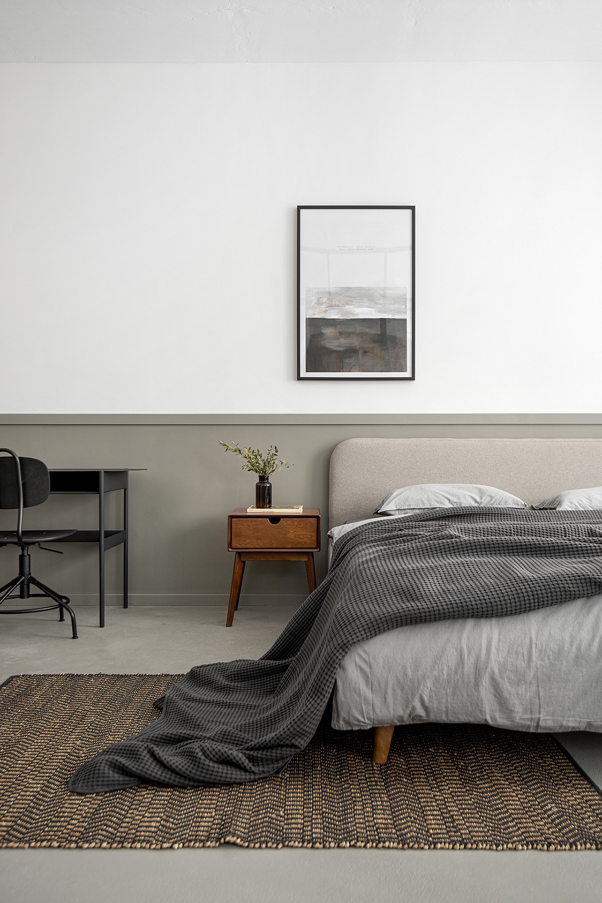Bên trong phòng ngủ, chiếc giường lấy cảm hứng từ phong cách hiện đại giữa thế kỷ với chăn ga màu xám trung tính. Thảm dệt mang đến cảm giác ấm áp.