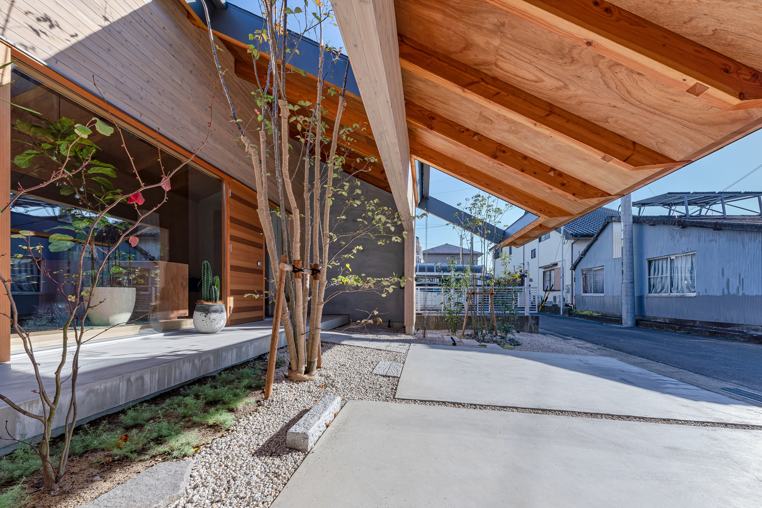 cận cảnh hệ mái hiên ngôi nhà ở Nhật, sân trước lát bê tông, cây xanh, cửa kính