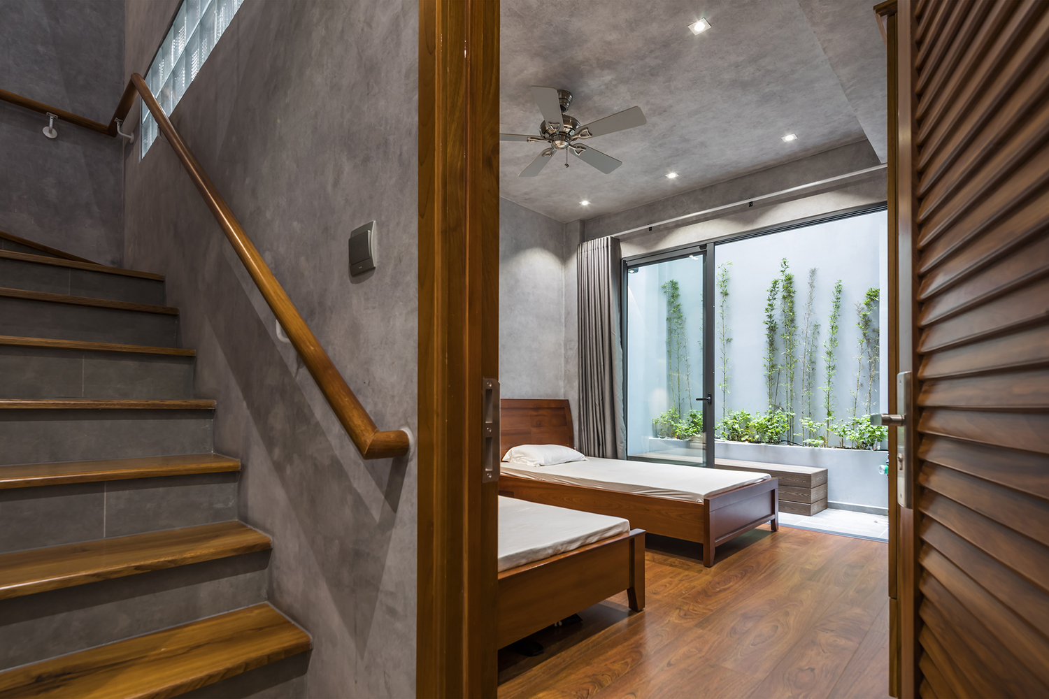 Thiết kế nội thất phòng ngủ tối giản với sàn gỗ ấm áp và cửa kính cao rộng cho phép ánh sáng tự nhiên ngập tràn không gian nhà.