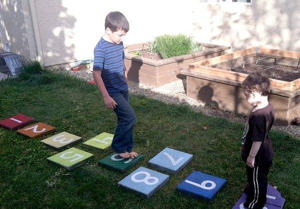hình ảnh 2 bé trai chơi nhảy lò cò trên thảm có đặt các con số