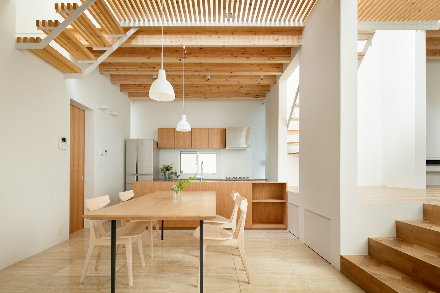 Toàn cảnh phòng bếp ăn với tường màu trắng, dầm gỗ, bàn ghế ăn bằng gỗ