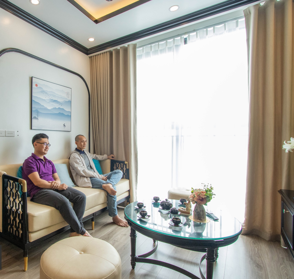 hình ảnh 2 người đàn ông ngồi trên sofa phòng khách căn hộ phong cách Indochine