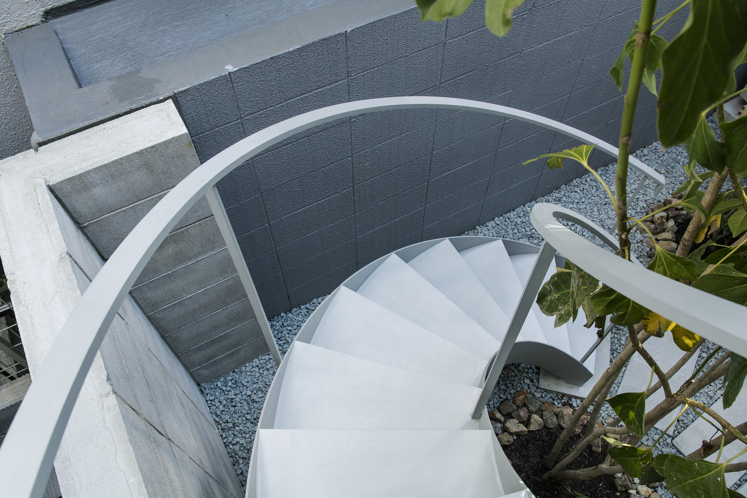 Cầu thang xoắn ốc nhỏ gọn bằng kim loại sơn trắng cung cấp lối tiếp cận lên tầng trên từ sân trước ngôi nhà ống điển hình ở Nhật Bản.