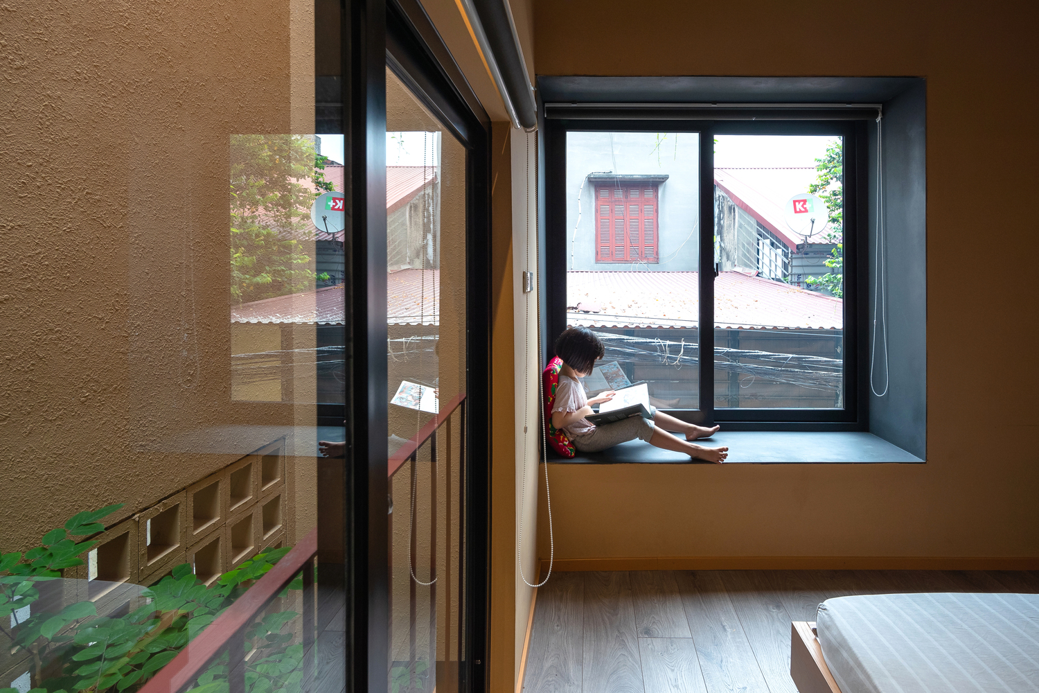 hình ảnh bé gái ngồi đọc sách trên bệ cửa sổ kính