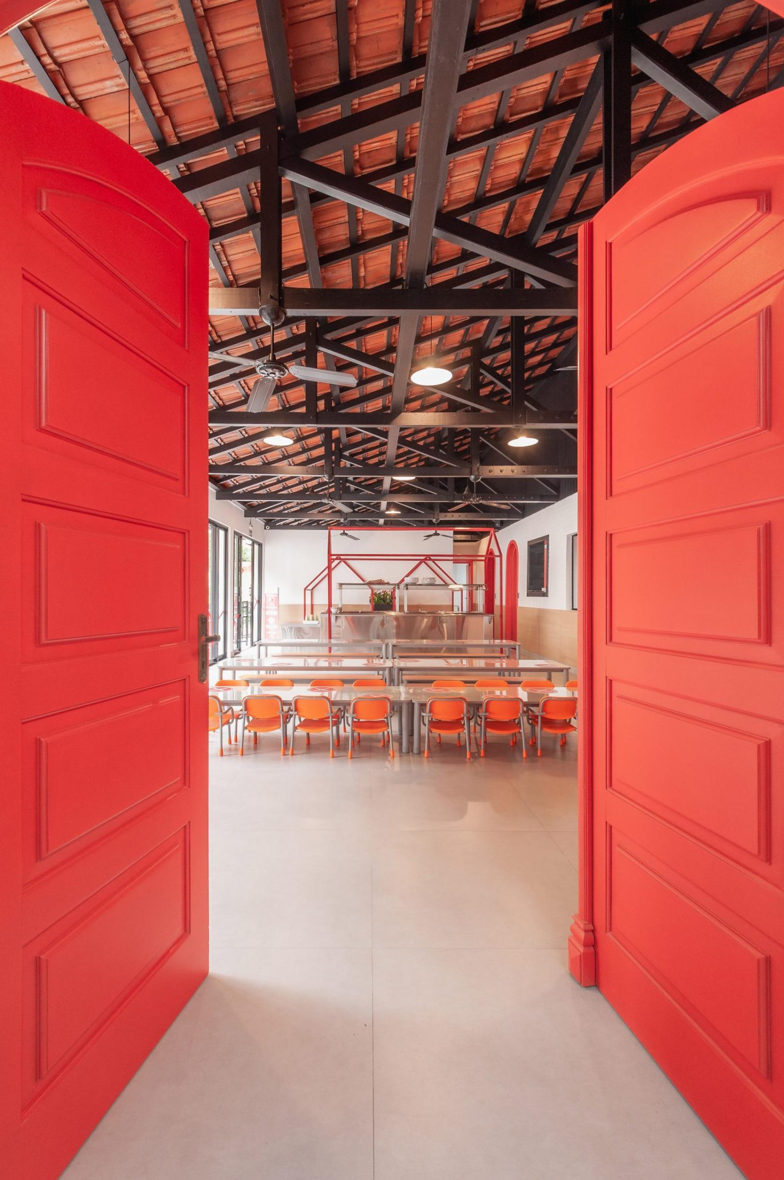 Cửa hai cánh cao rộng sơn màu đỏ cam dẫn lối vào phòng ăn.
