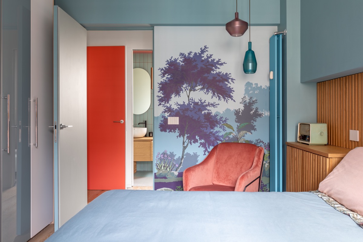 Phòng ngủ ấn tượng với bức tranh tường khu rừng mơ mộng hài hòa cùng phông nền màu xanh lam chủ đạo. Ghế màu đỏ sẫm tạo sự đối lập ấm áp với bảng màu xanh lam mát mẻ. 