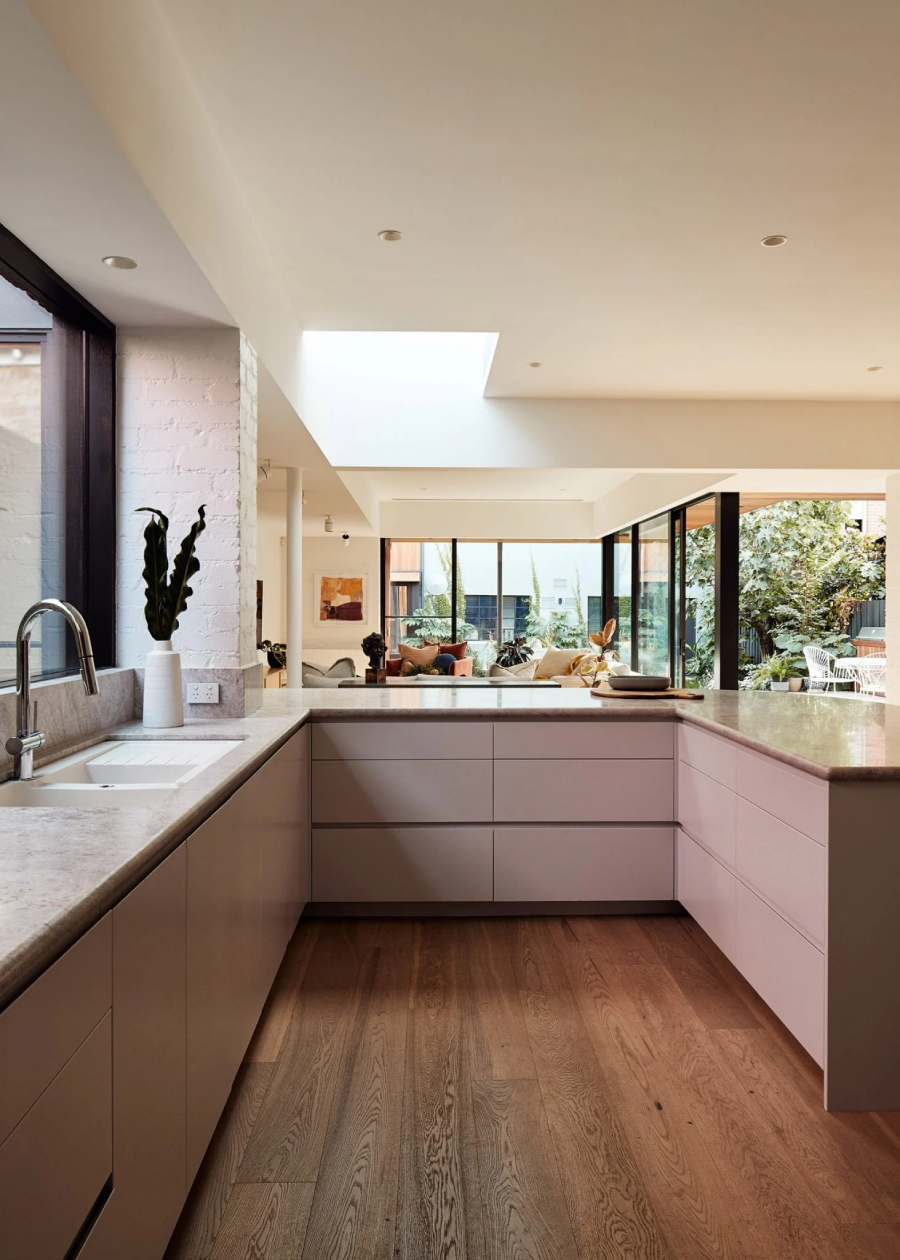 Phòng bếp được chiếu sáng bởi giếng trời trên mái. Mặt bàn bằng đá cẩm thạch phía trên tủ màu hồng, mở rộng ra khỏi tường theo hình chữ J để tạo ra không gian nấu nướng và chuẩn bị thực phẩm rộng rãi, thoải mái.