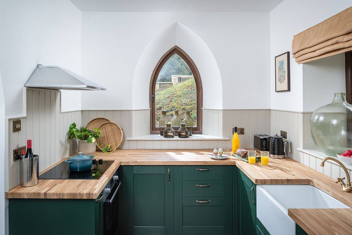 Thiết kế cửa sổ sáng tạo kết hợp với tủ màu xanh đậm và mặt bàn bằng gỗ cho nhà bếp nhỏ phong cách chiết trung lạ mắt.