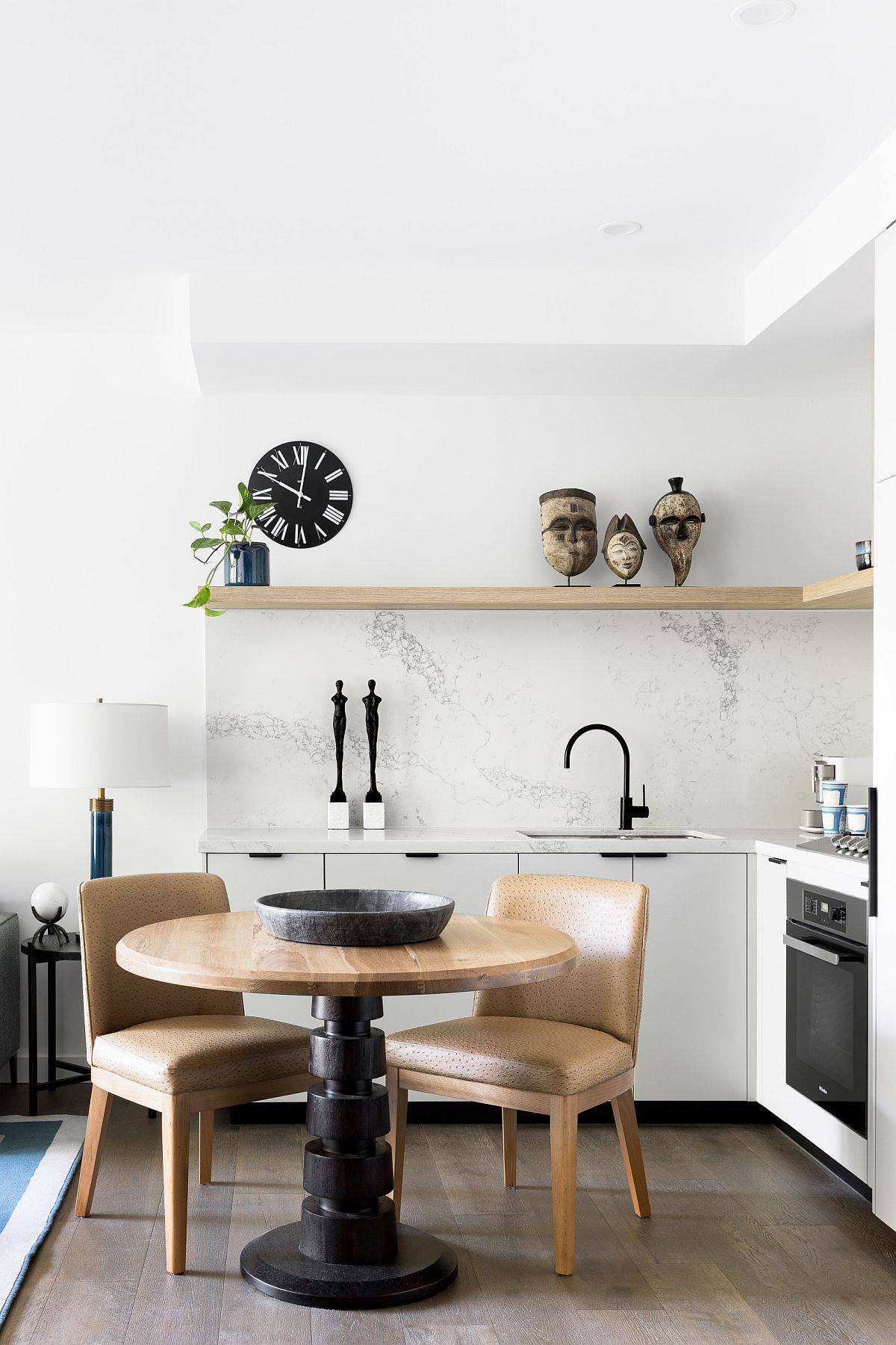 Nhà bếp màu trắng đương đại với đá cẩm thạch ốp lát và một kệ gỗ nổi.