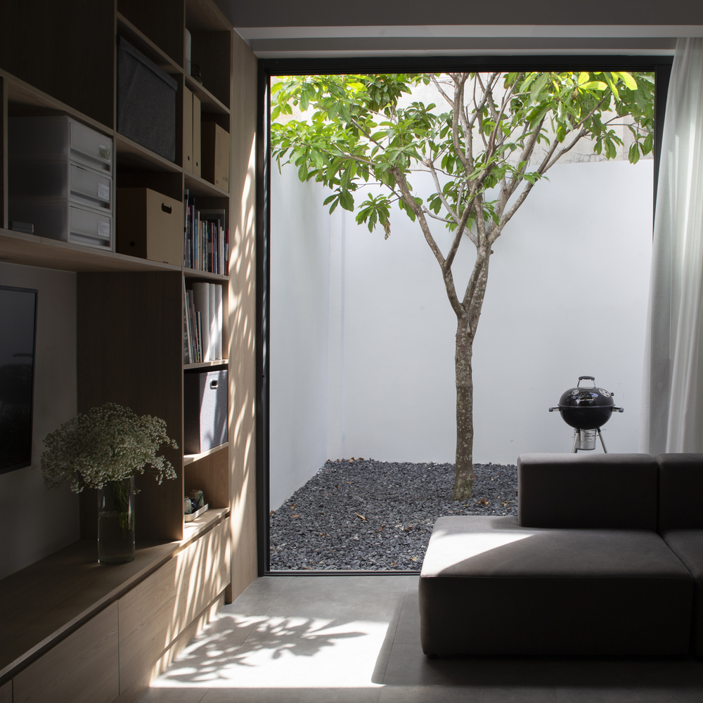 hình ảnh một góc nhà phố với phòng khách, hệ kệ gắn tường, sân trong trồng cây.