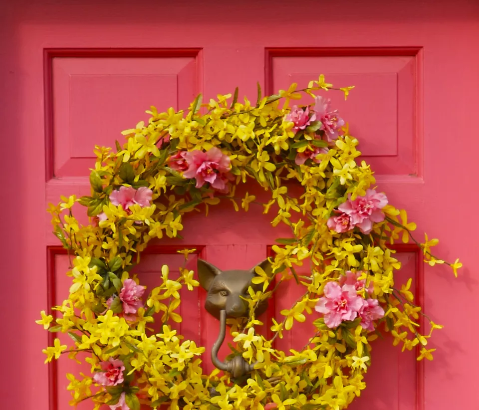 cửa chính sơn màu hồng, treo vòng hoa màu vàng
