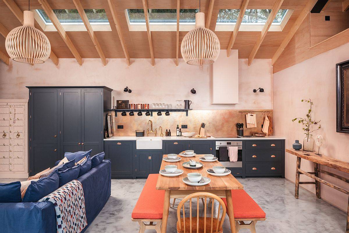 Phòng bếp phong cách Scandinavian bắt mắt với những bức tường màu hồng nhạt và sắc cam nổi bật ở băng ghế đôi khu vực bàn ăn.