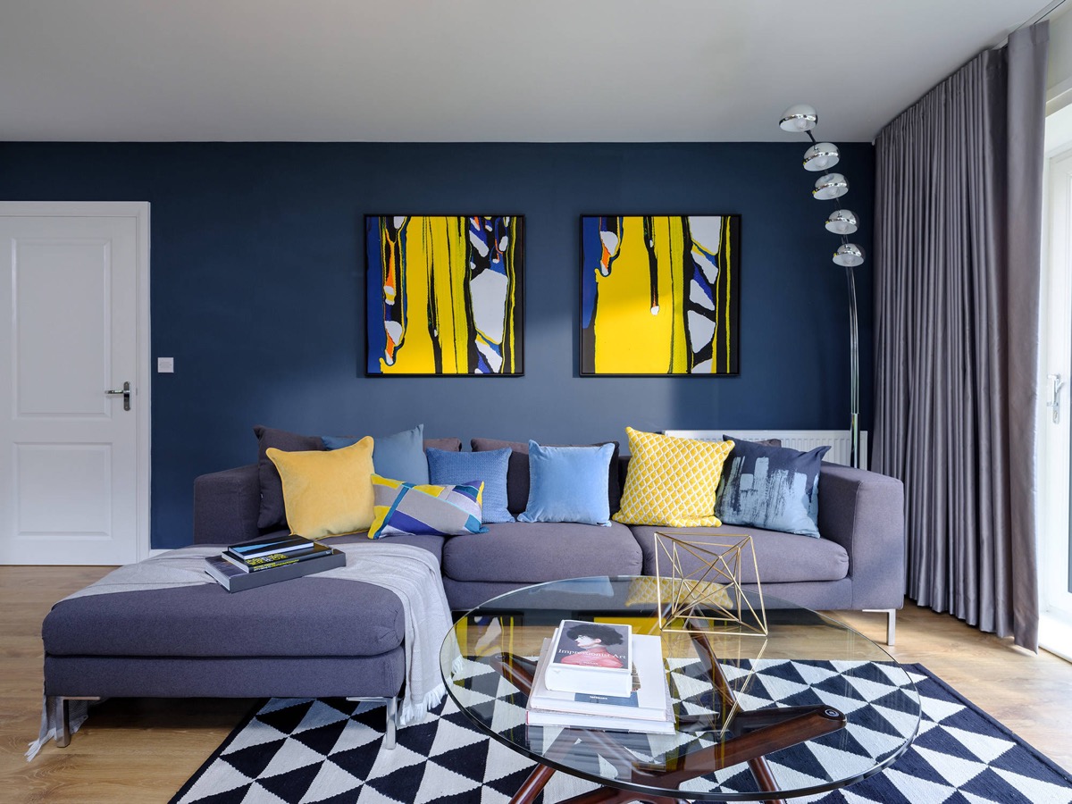 Mẫu thiết kế nội thất phòng khách màu xanh đậm chất nghệ thuật với các điểm nhấn màu vàng nắng có độ tương phản cao so với phần còn lại của căn phòng.