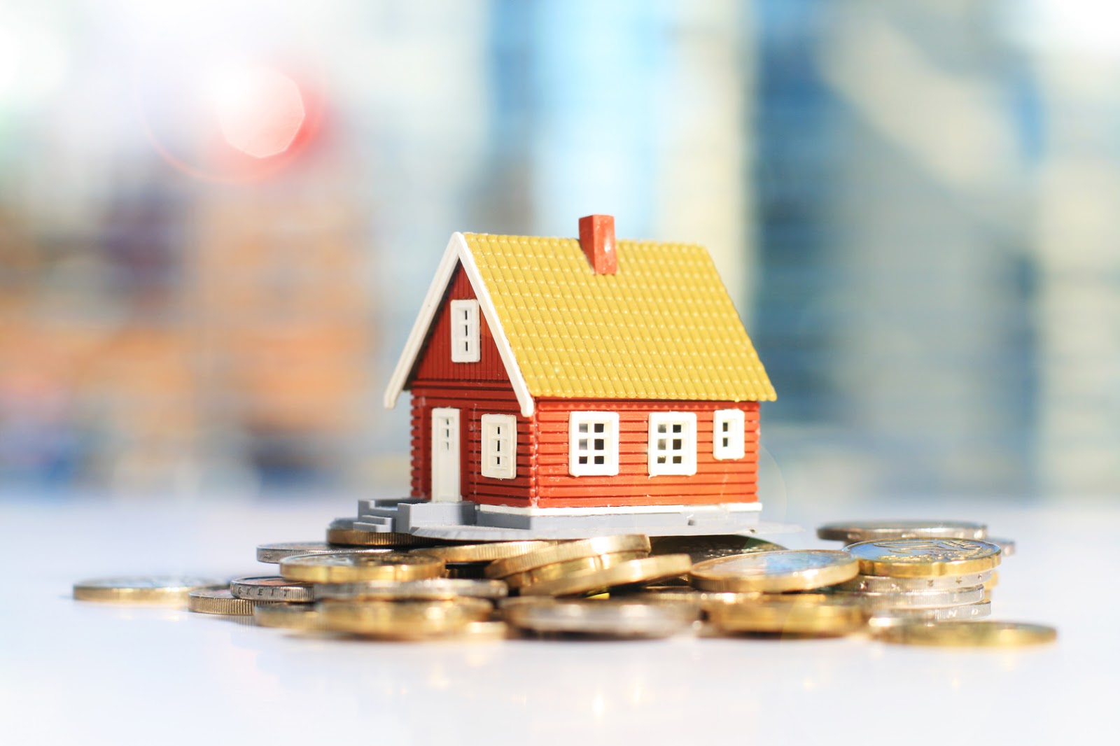 hình ảnh cận cảnh mô hình ngôi nhà đặt trên đống tiền xu minh họa cho việc tiết kiệm tiền mua nhà