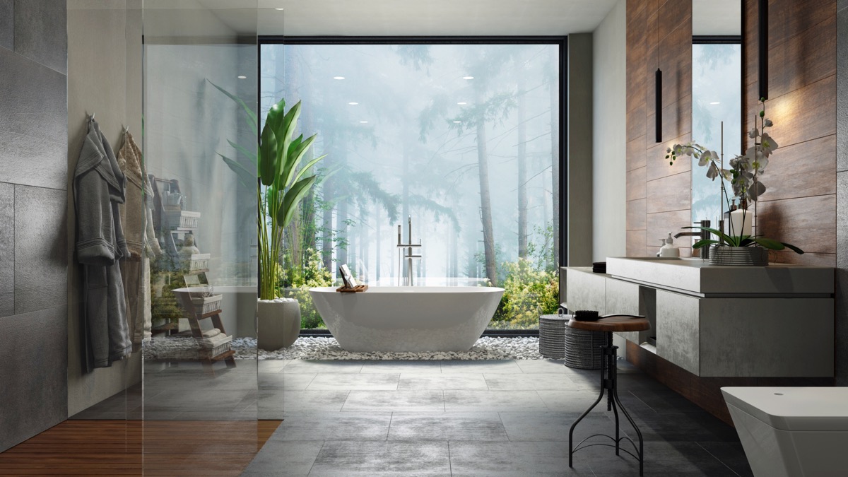 Mẫu phòng tắm đẹp với tông màu xám bê tông mộc mạc, làm phông nền cho cây xanh thêm phần nổi bật. Bức tranh phong cảnh rừng nhiệt đới tạo chiều sâu cho không gian.