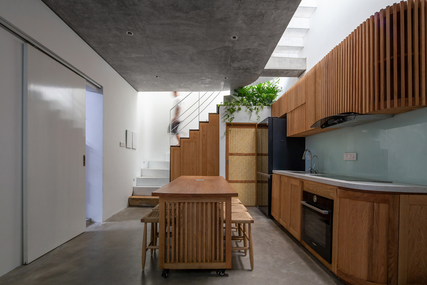 Nhà bếp và phòng ăn nằm ở tầng trệt. Không gian này được thiết kế để đón sáng tự nhiên tối đa từ tầng mái, giếng trời và các khoảng trống.