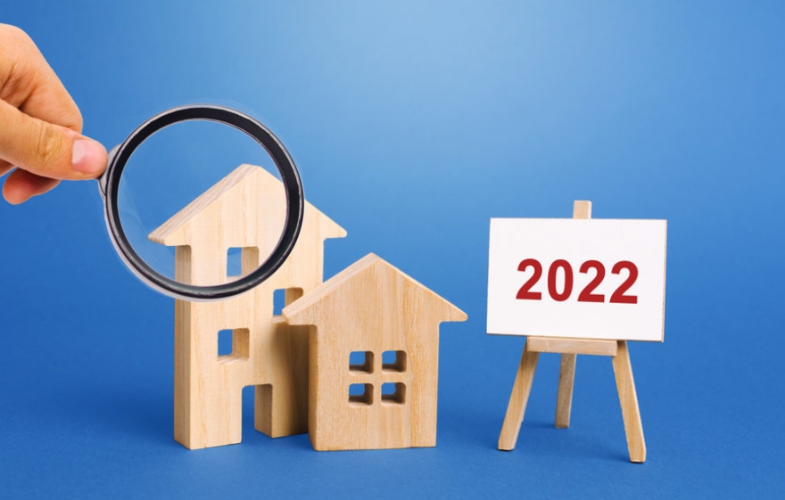 hình ảnh kính lúp soi 2 mô hình ngôi nhà bằng gỗ biểu thị cho thị trường bất động sản toàn cầu năm 2022