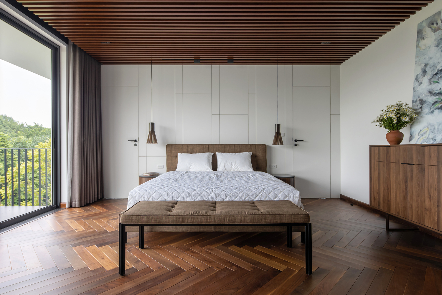 Không gian phòng ngủ thoáng rộng, bài trí nội thất hiện đại tối giản với chất liệu gỗ màu cánh gián ấm áp cho cà sàn và lam trên trần nhà.
