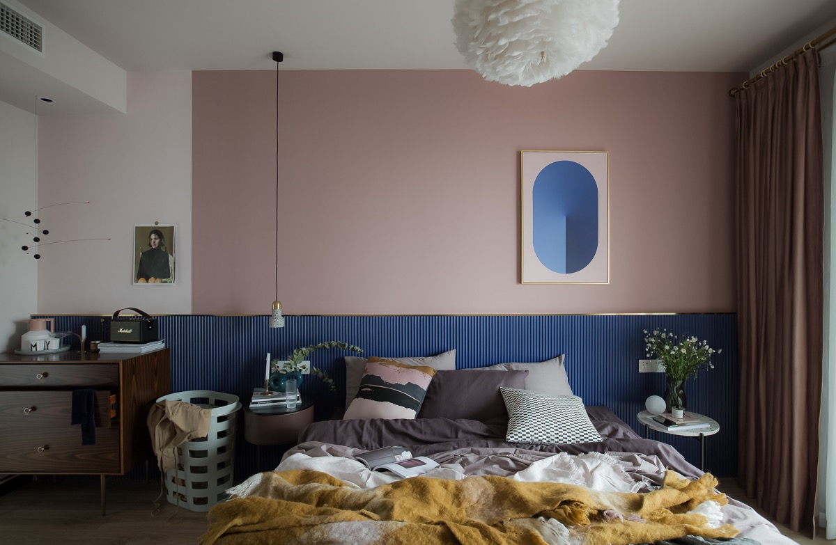 Trong phòng ngủ master, bức tường đầu giường màu hồng và xanh lam được ngăn bằng điểm nhấn màu vàng kim loại lấp lánh.