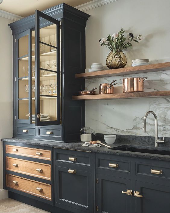 Tủ bếp màu đen với tay nắm mạ đồng nổi bật, kệ gỗ gắn tường, tủ kính đựng ly thủy tinh