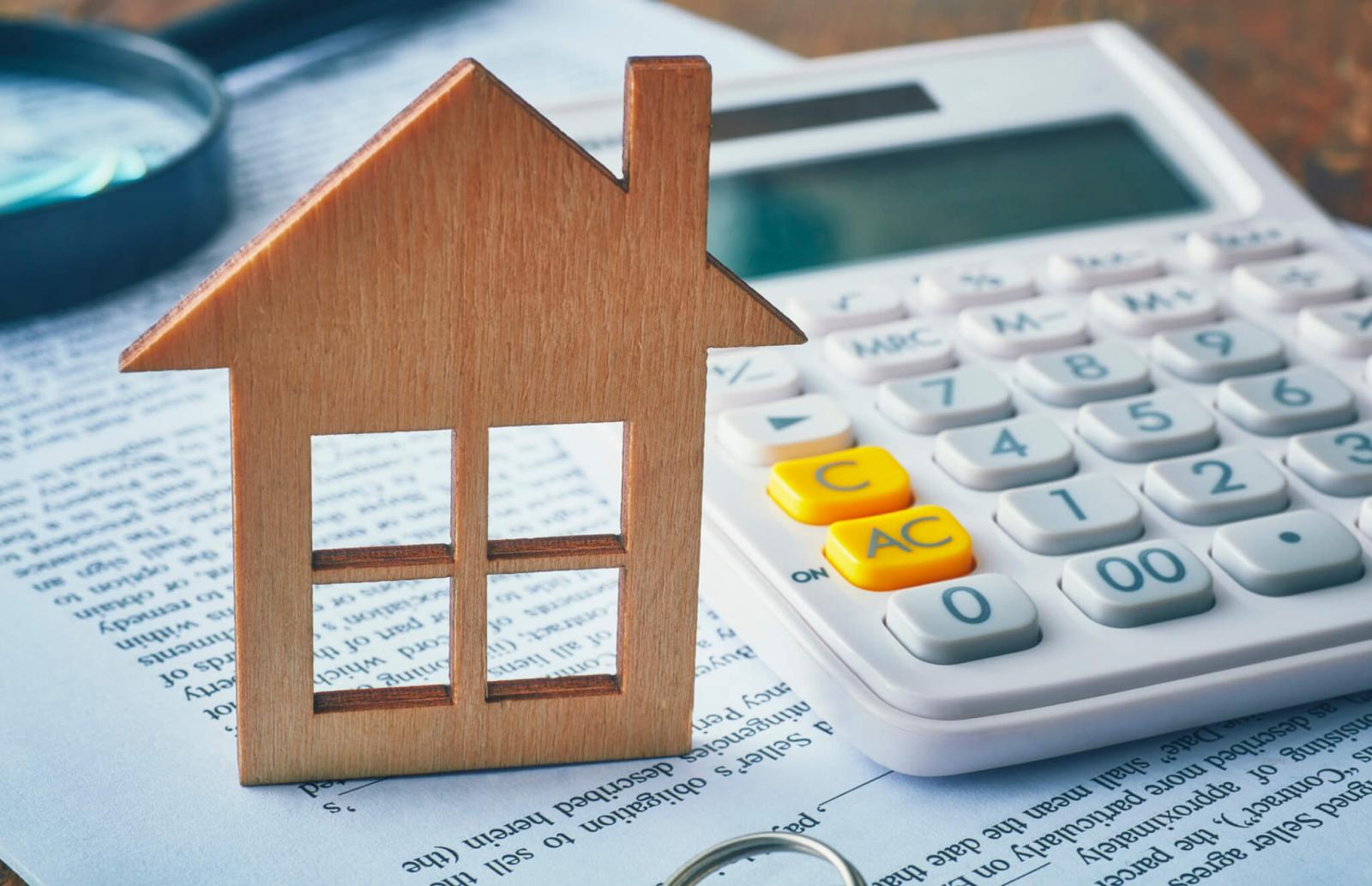 hình ảnh mô hình ngôi nhà, máy tính casio, tài liệu, kính lúp minh họa cho thuế thu nhập cá nhân khi bán nhà