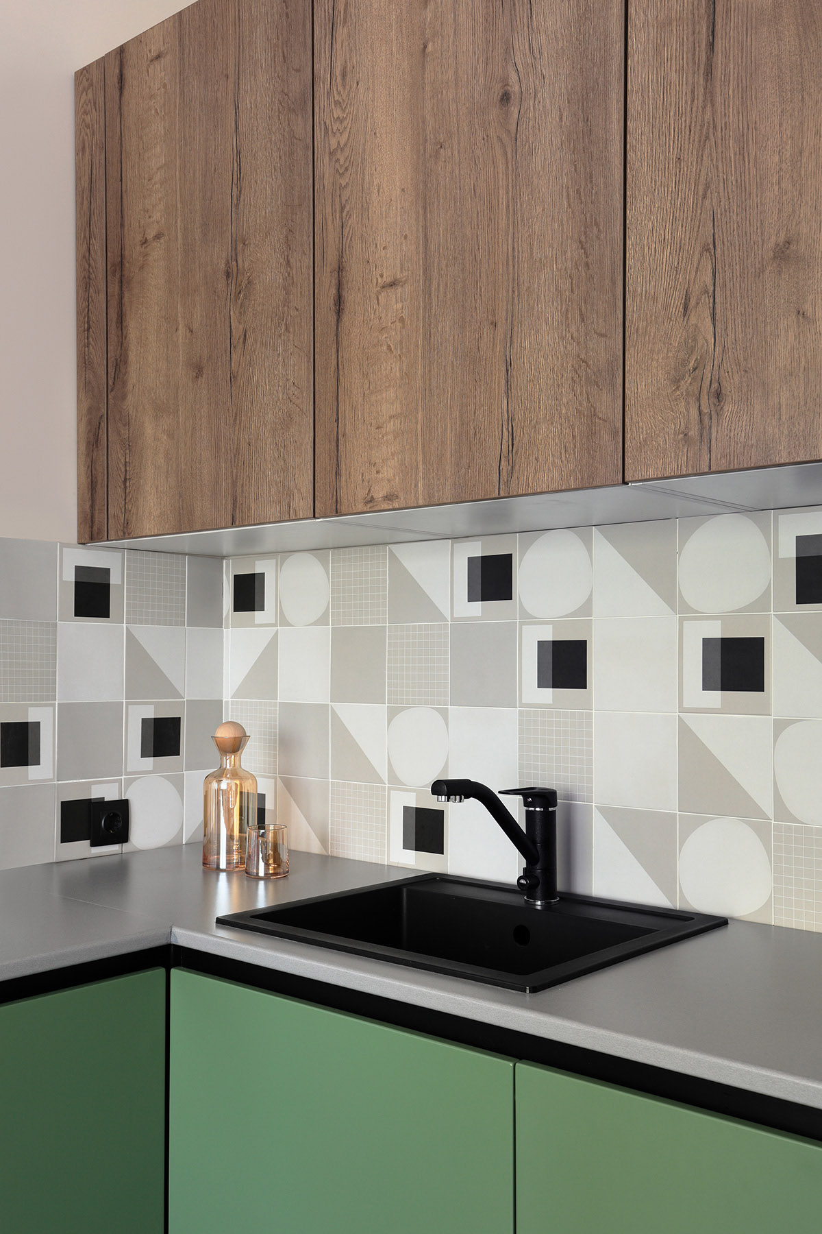 Gạch ốp tường bếp hình học nổi bật quanh nhà bếp. Bồn rửa màu đen hài hòa với bề mặt bàn bếp màu xám sang trọng.