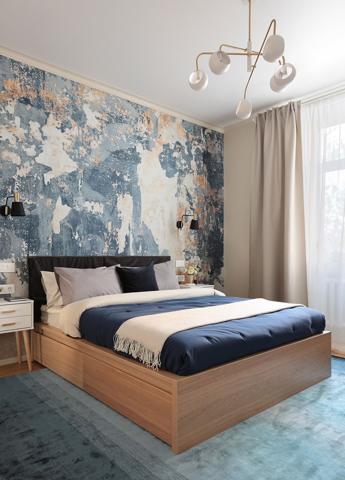 Bức tường màu xanh đằng sau đầu giường và thảm trải sàn cùng tông tạo cảm giác thư giãn, thoáng mát cho không gian ngủ nghỉ.