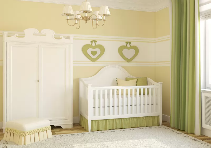 phòng ngủ trẻ sơ sinh với tường sơn màu xanh lá cây nhạt, tủ mfu trắng, giường cũi cho bé