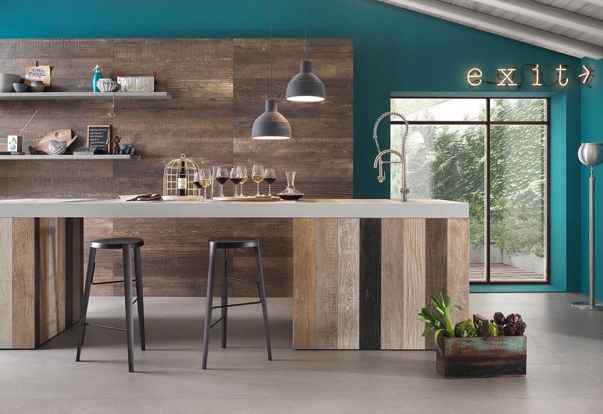 Phòng bếp ấn tượng với sự kết hợp giữa các vật liệu hiện đại và hình dạng công nghiệp cổ điển. Đèn thả mặt dây chuyền màu xám tương phản với sắc xanh lá cây, xanh dương, vàng.