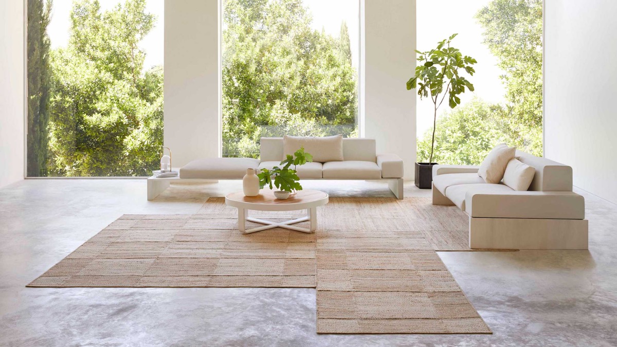 Phòng khách sử dụng nội thất làm từ vật liệu tự nhiên (gỗ, đá, thảm đay) để bổ sung cho một bức tranh toàn cảnh rợp bóng cây. 