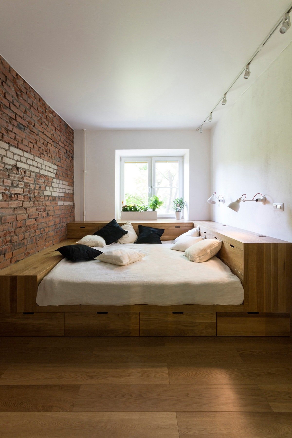 Khối giường bằng gỗ tích hợp ngăn kéo lưu trữ gọn đẹp. Các bề mặt xung quanh đảm nhiệm vai trò bàn phấn, bàn làm việc tiện dụng.